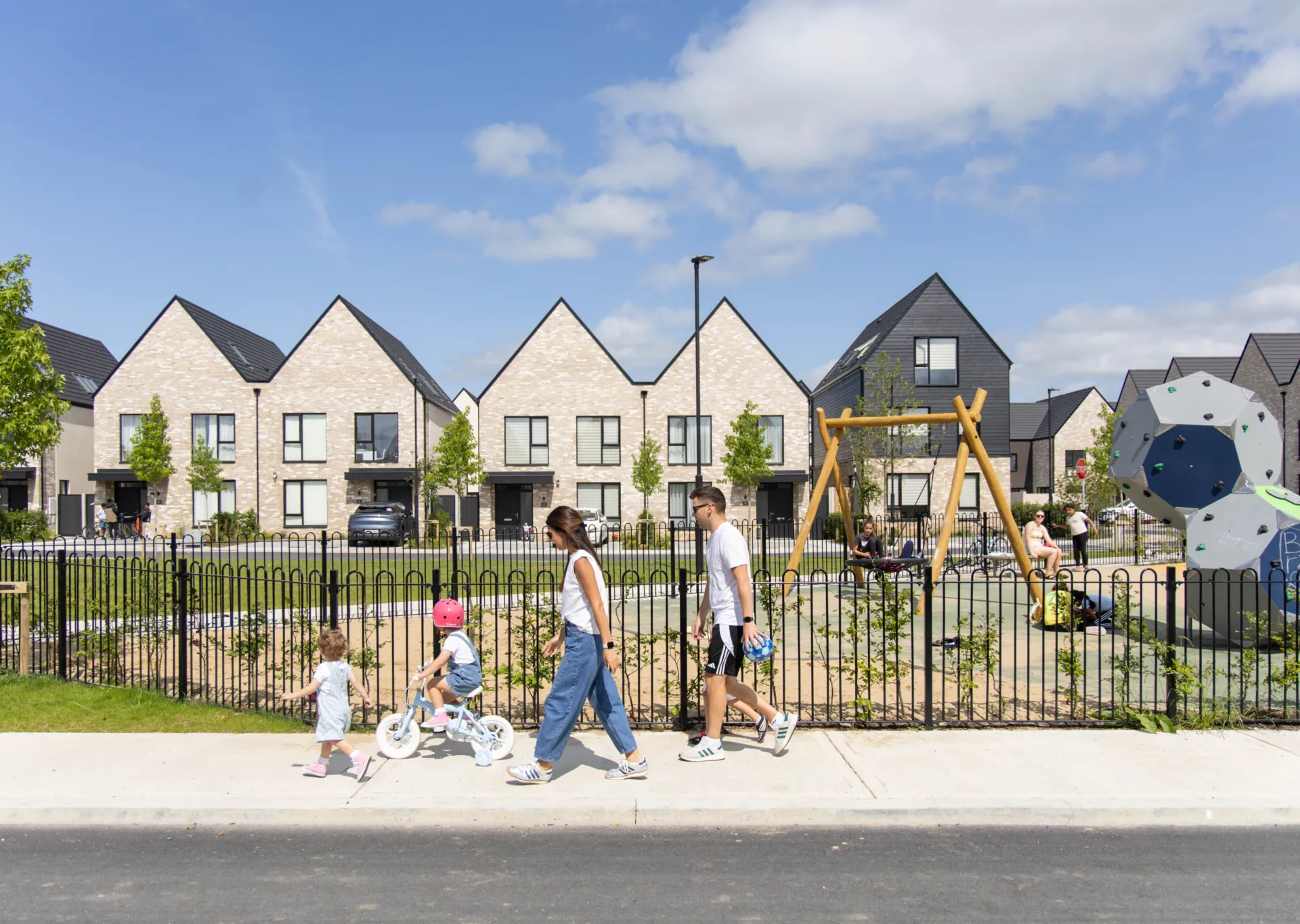 A photograph of Sand Wood, Portlaoise, a family walk past a play area at the new development
