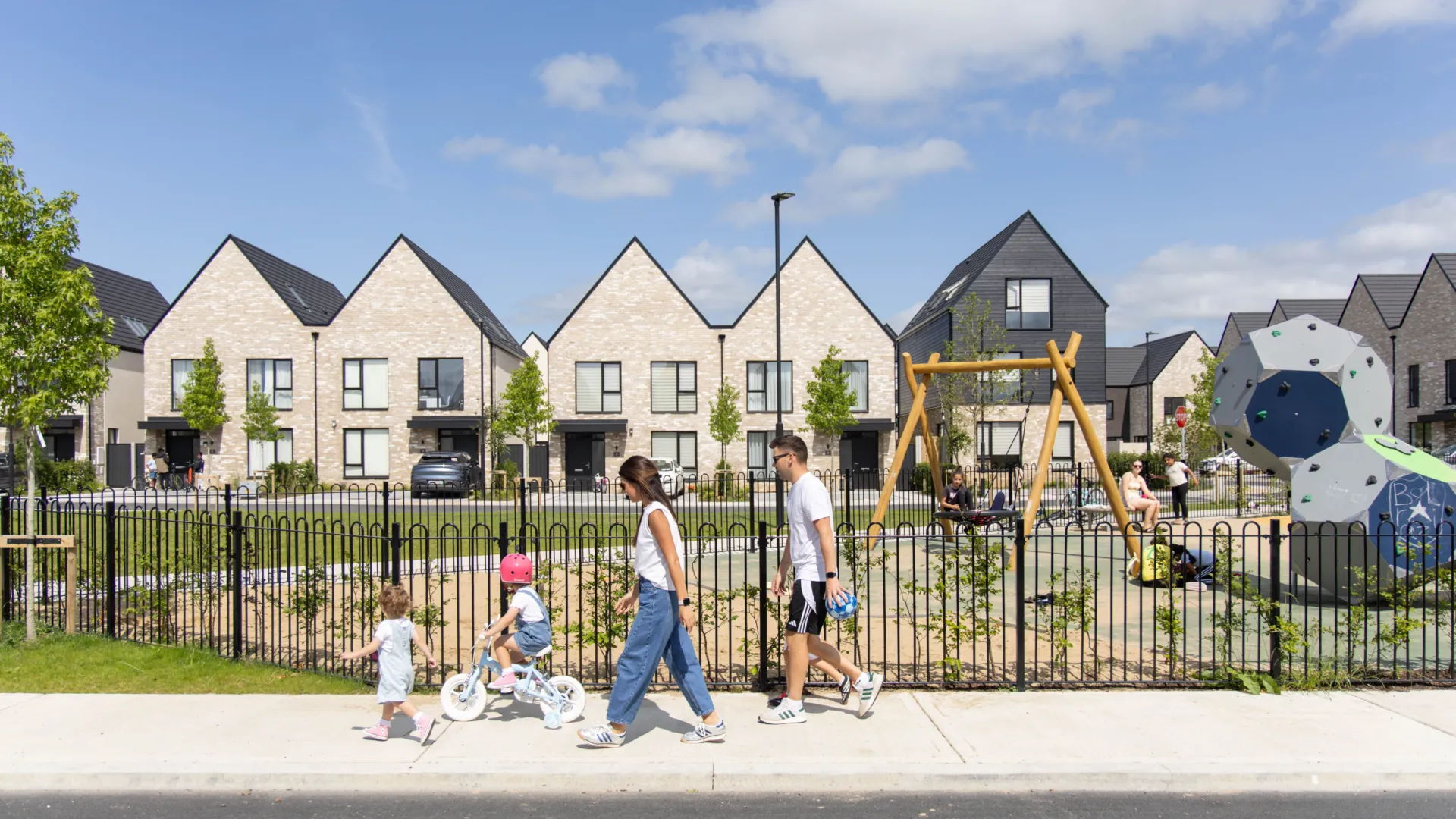 A photograph of Sand Wood, Portlaoise, a family walk past a play area at the new development