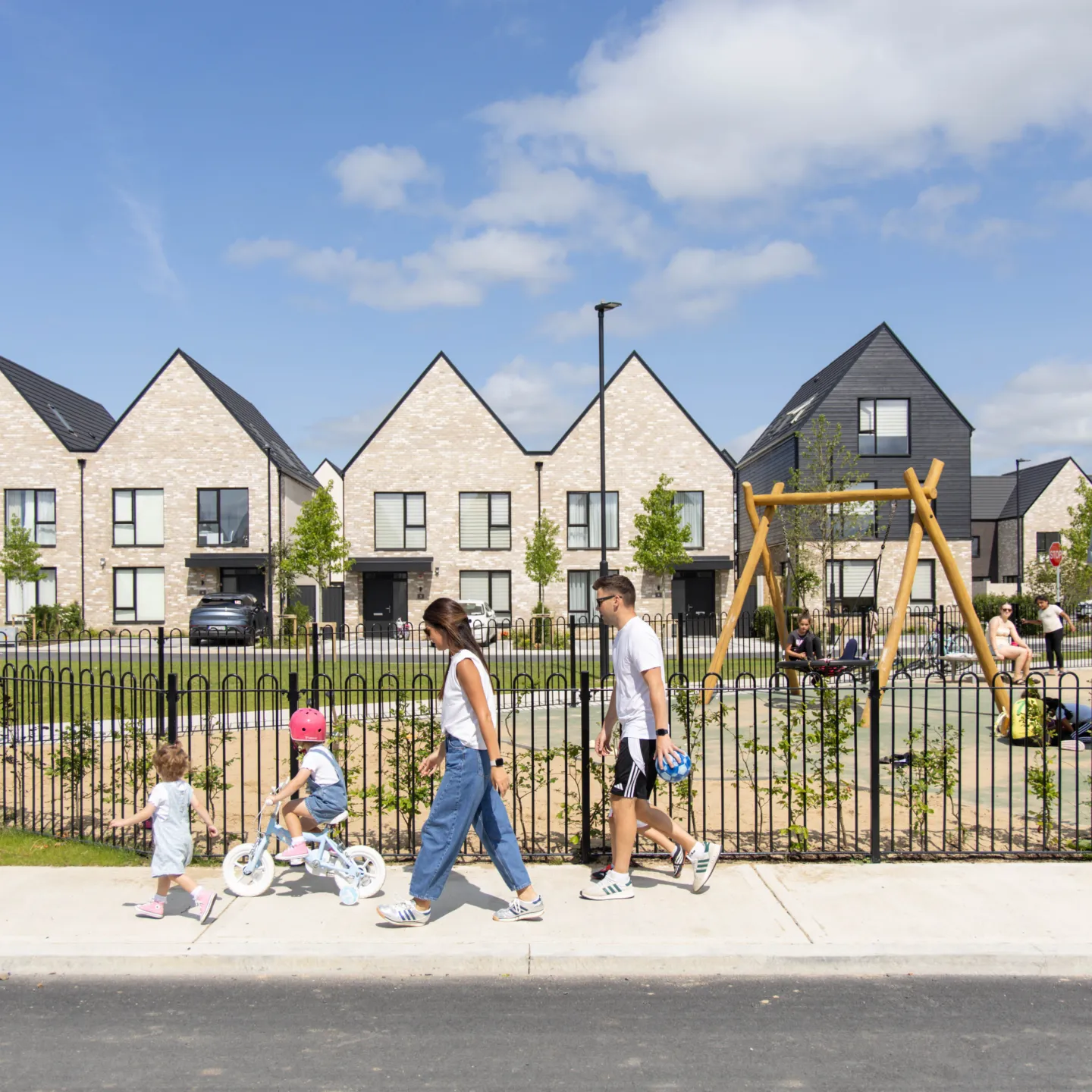 A photograph of Sand Wood, Portlaoise, a family walk past a play area at the new development