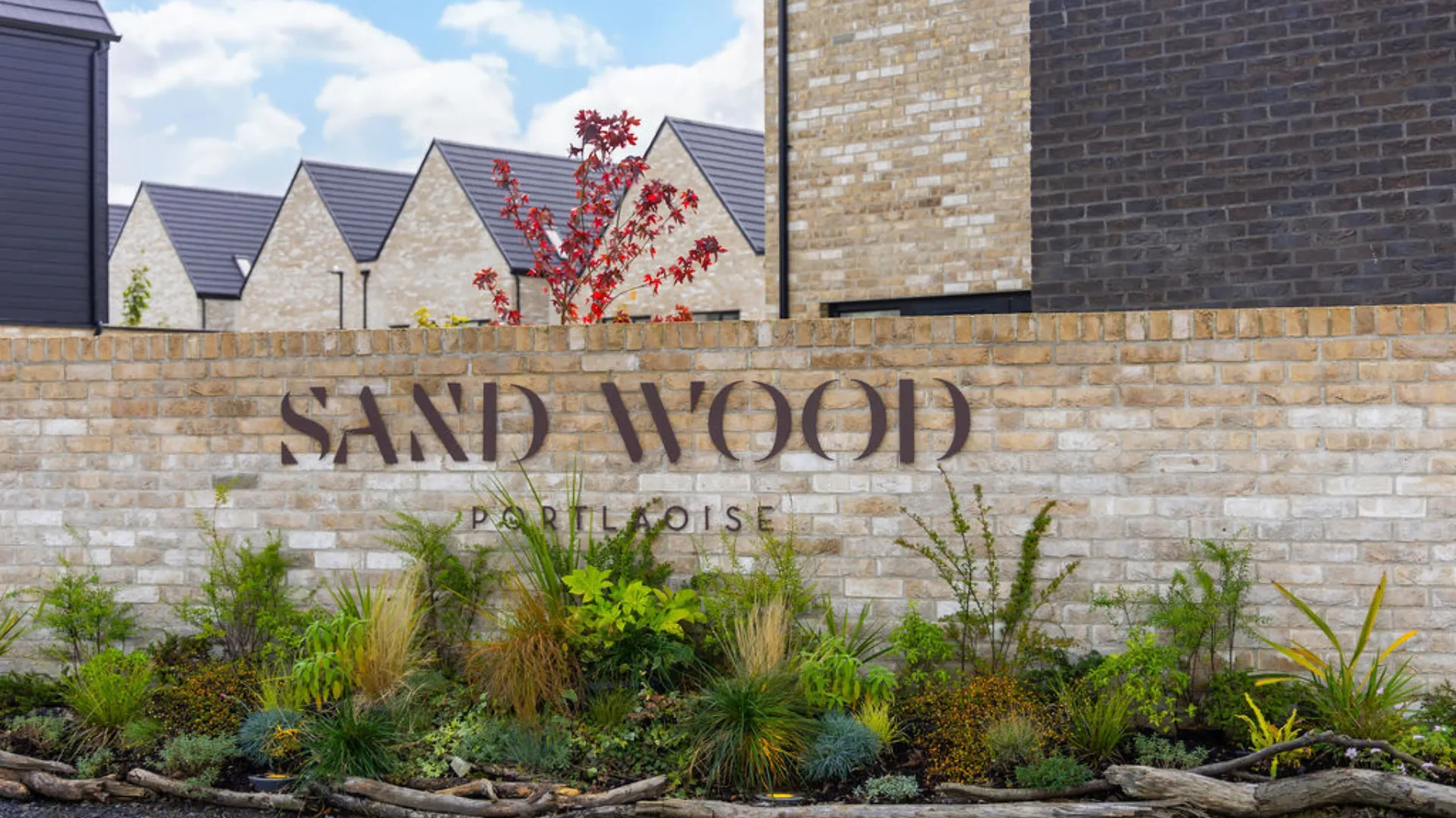 The Sand Wood Logo on the yellow boundary brick wall