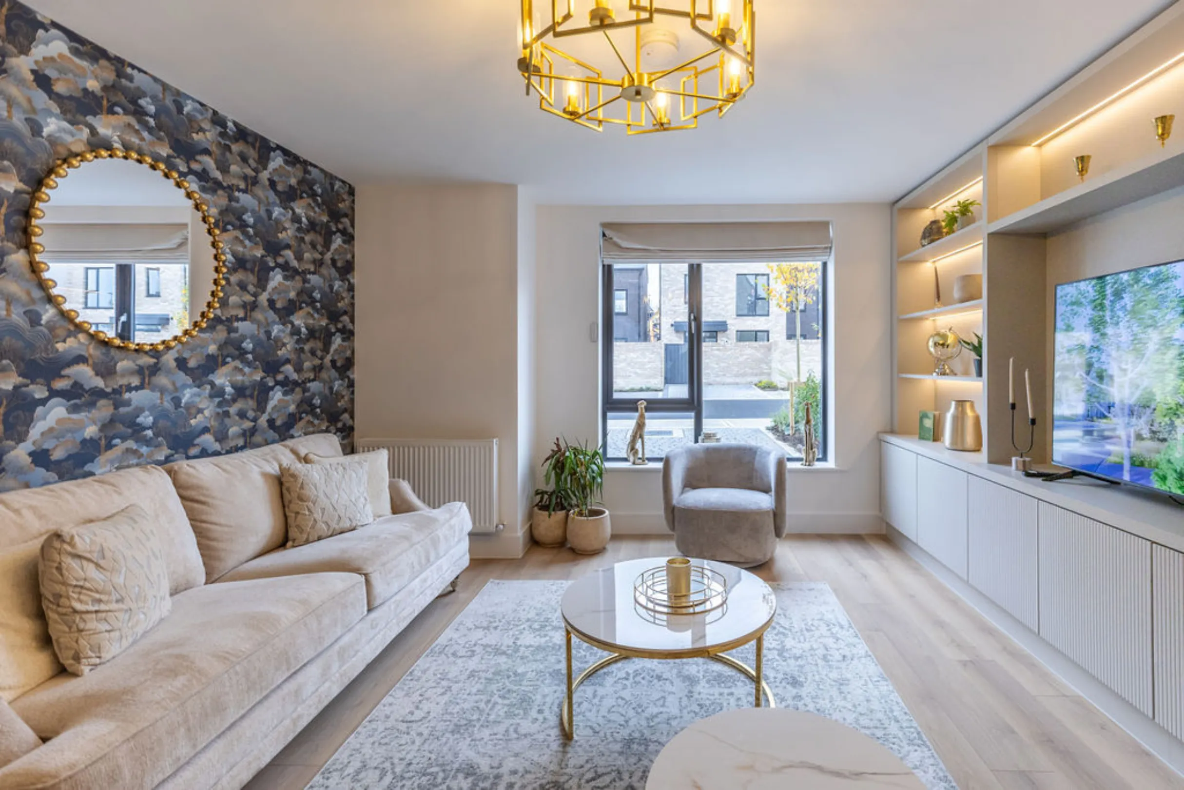 The image showcases a modern living room with a neutral color palette and stylish decor. The room features a sofa, a coffee table, a built-in entertainment unit, and a large window.