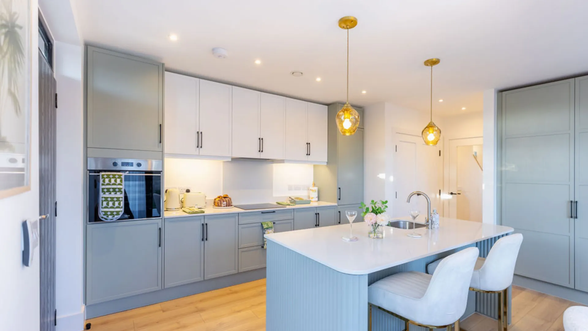 A modern kitchen with island and bar stools.  The kitchen has built in appliances.