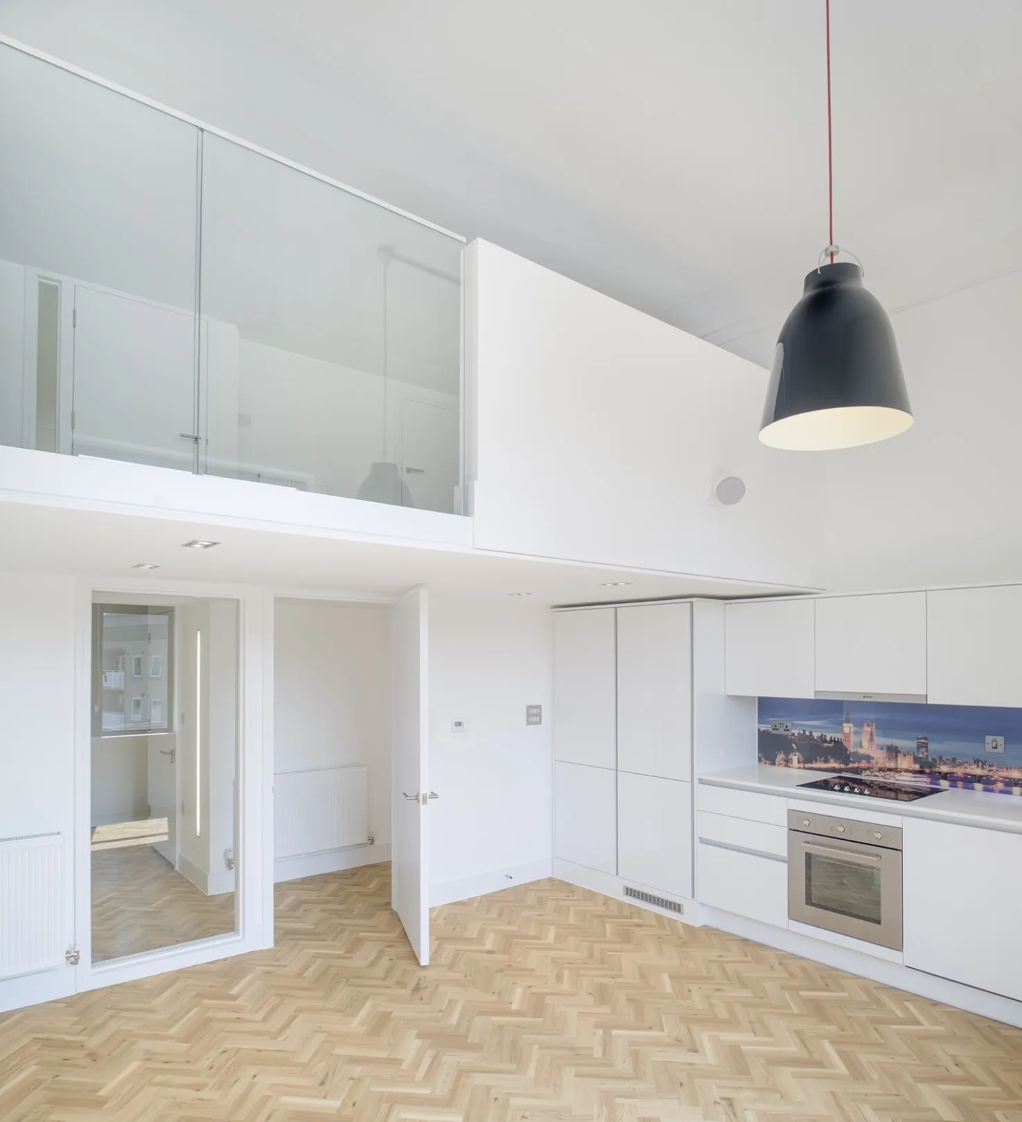Modern interior split-level living space with kitchen below and a mezzanine above. Parquet floor throughout.