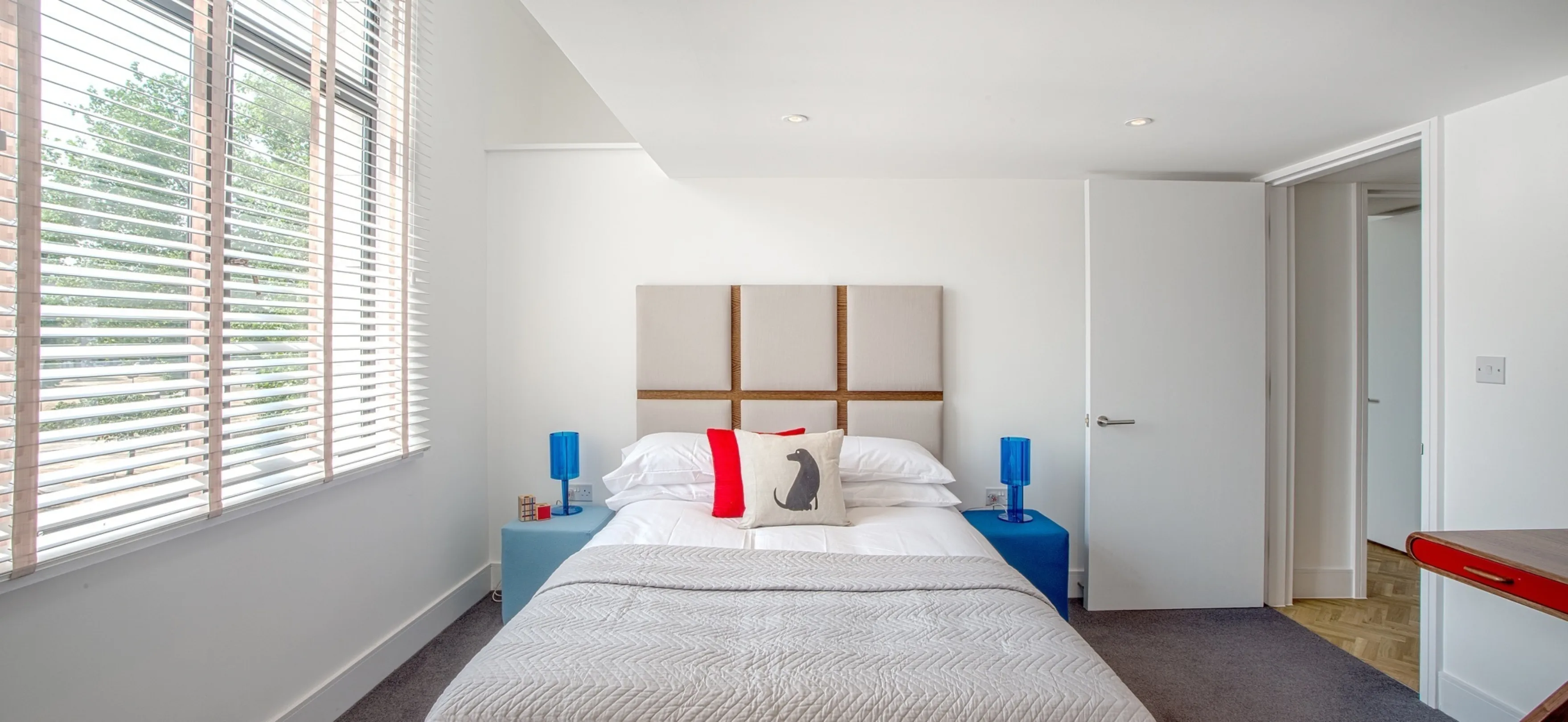 Modern bedroom interior with matching night-stand tables and a large window flooding the room with daylight