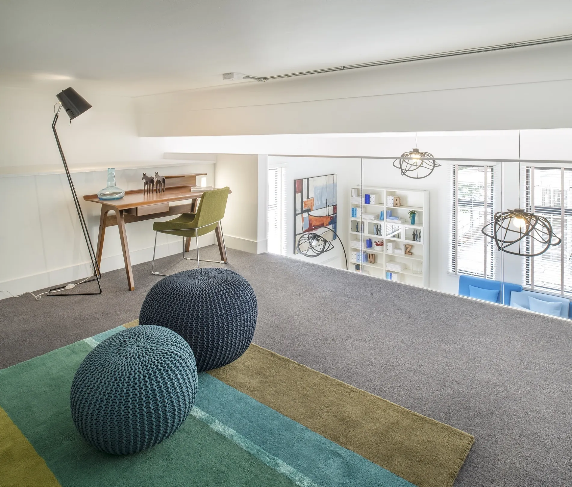 Modern interior mezzanine level with desk space and soft furnishings, overlooking a living room.