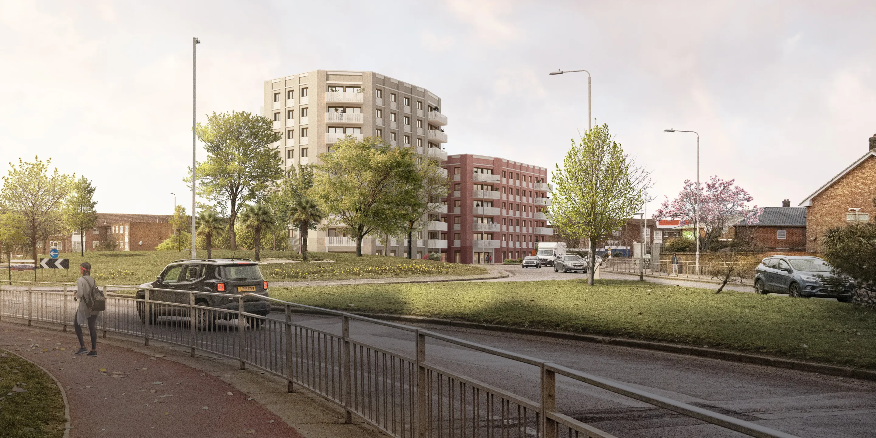 A car and a woman approach a planted roundabout with two large modern residential buildings in the background