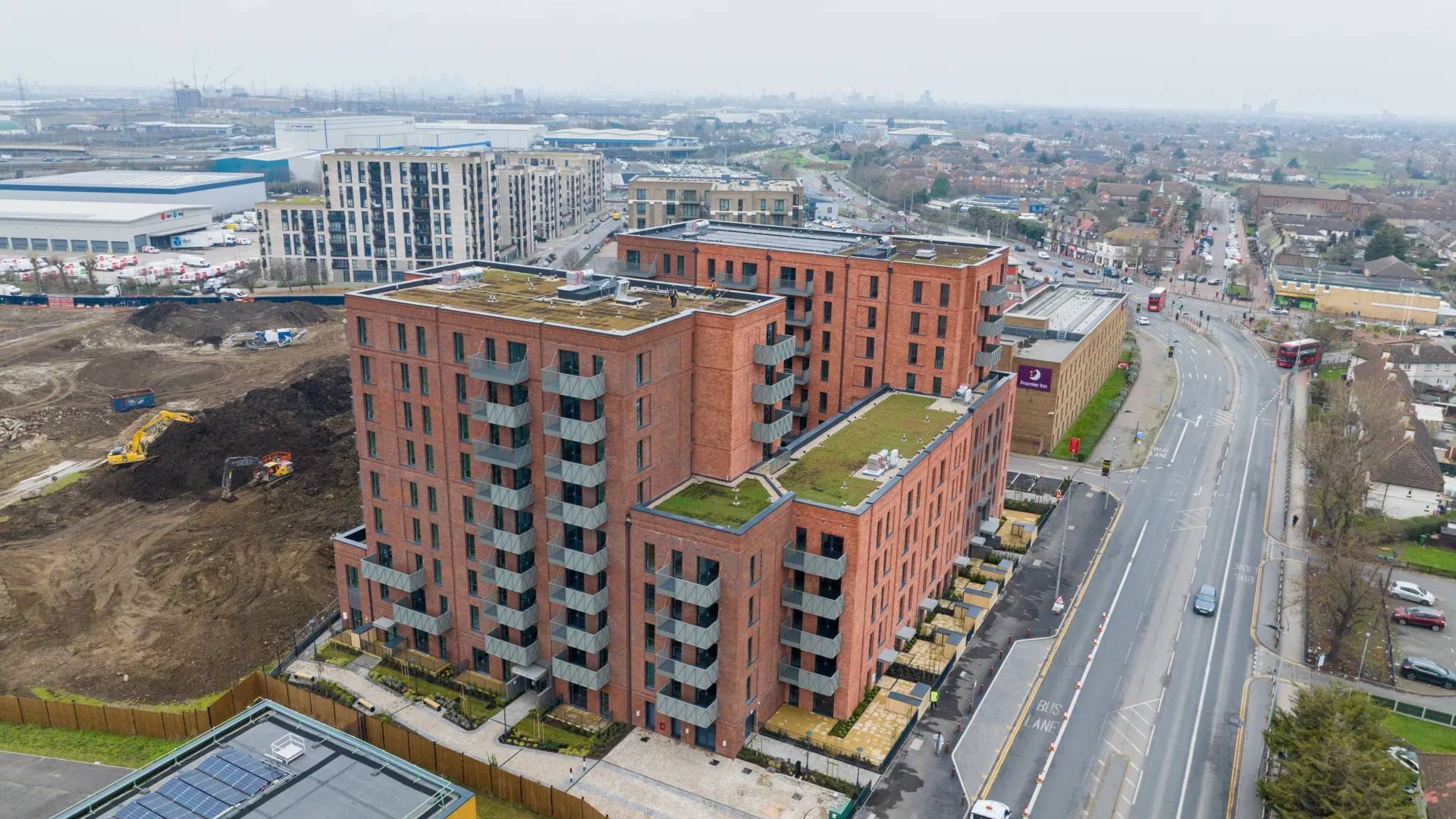 An aerial image of a new build red brick building with green roofs in Dagenham