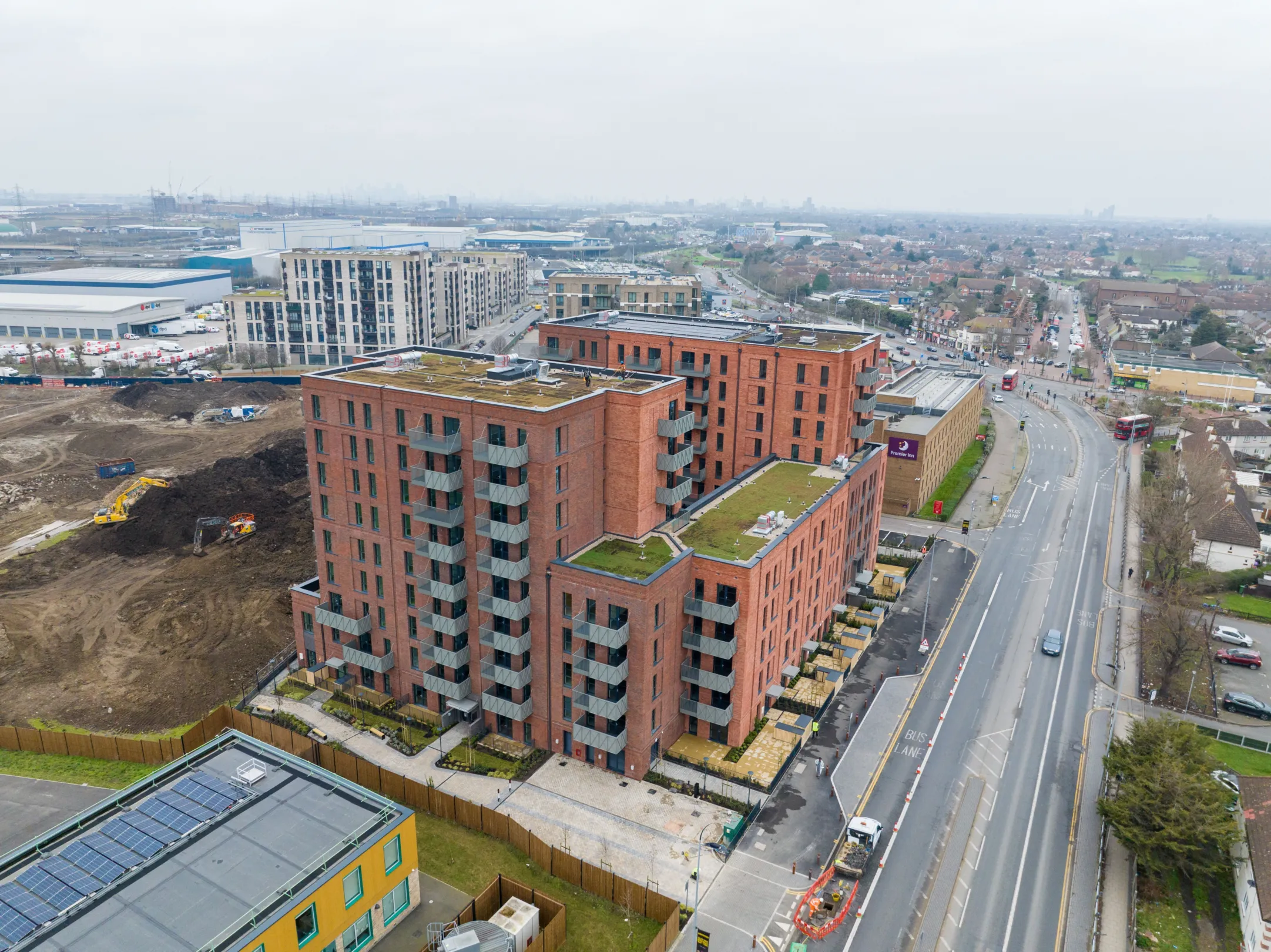 An aerial image of a new build red brick building with green roofs in Dagenham