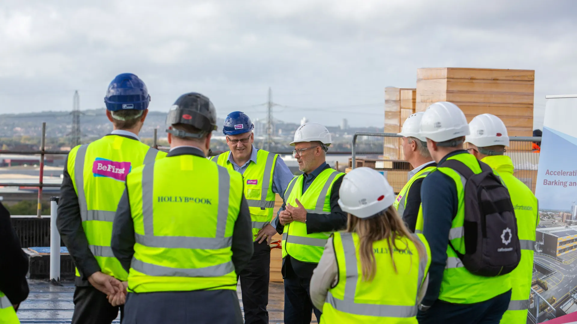 Group of people on a roof of a new build construction development, wearing high-viz vests and hard hats.