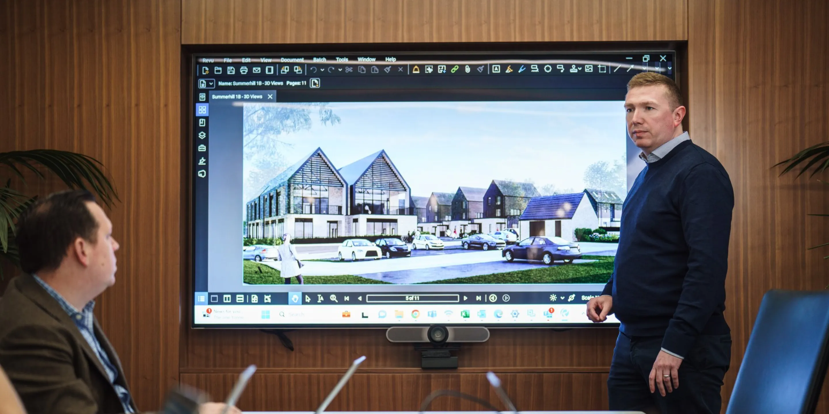 Man in front of screen in a meeting room presenting a development to collegues