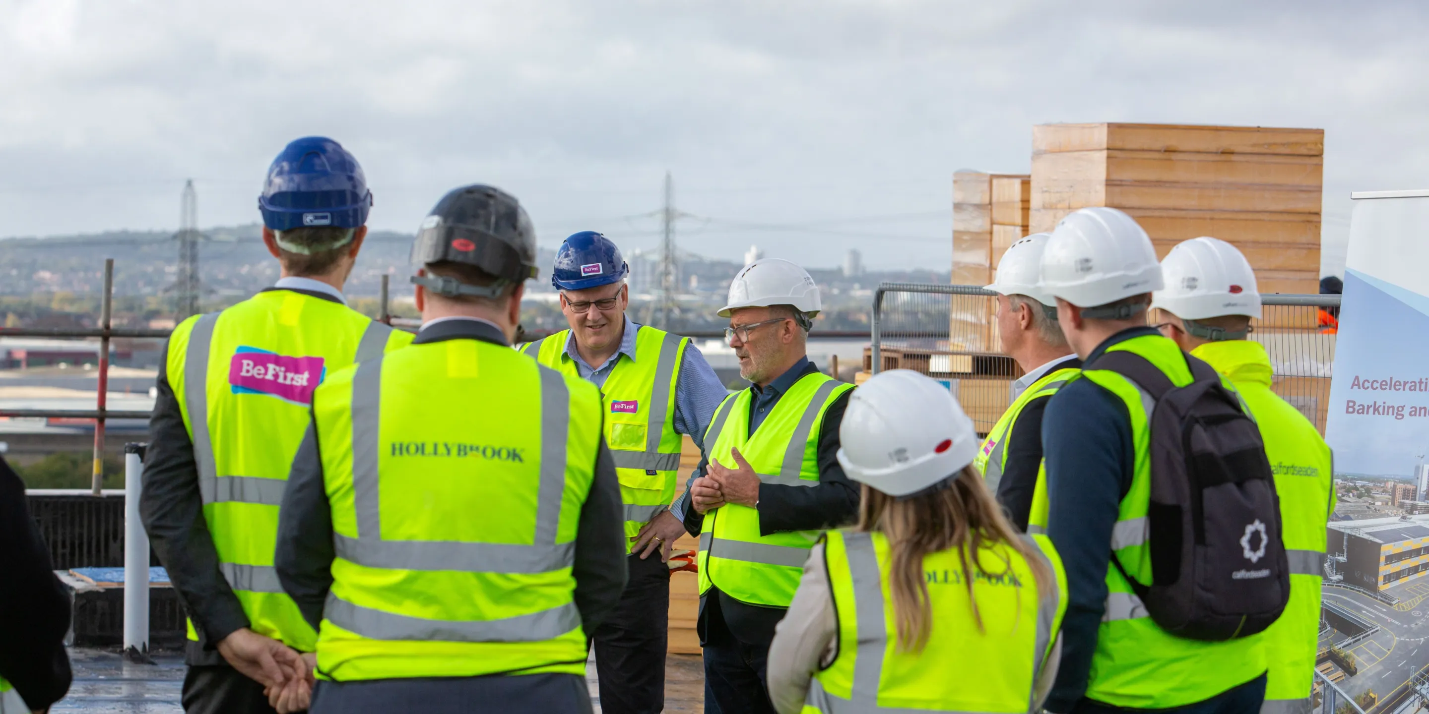 Group of people on a roof of a new build construction development, wearing high-viz vests and hard hats.