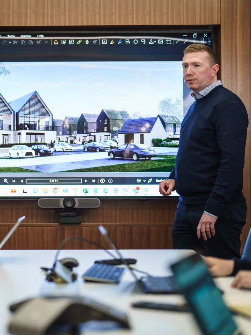 Man in front of screen in a meeting room presenting a development to collegues